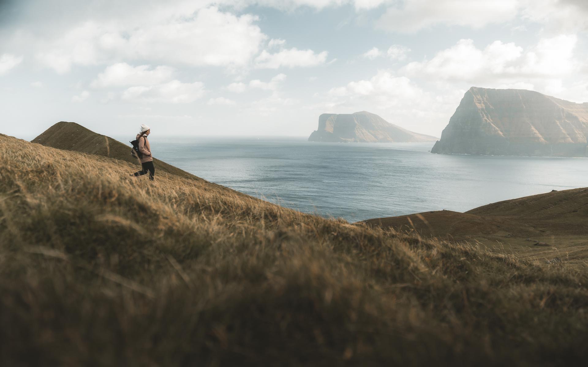 Female walking on the mountains in Faroe Islands by Rob Ash