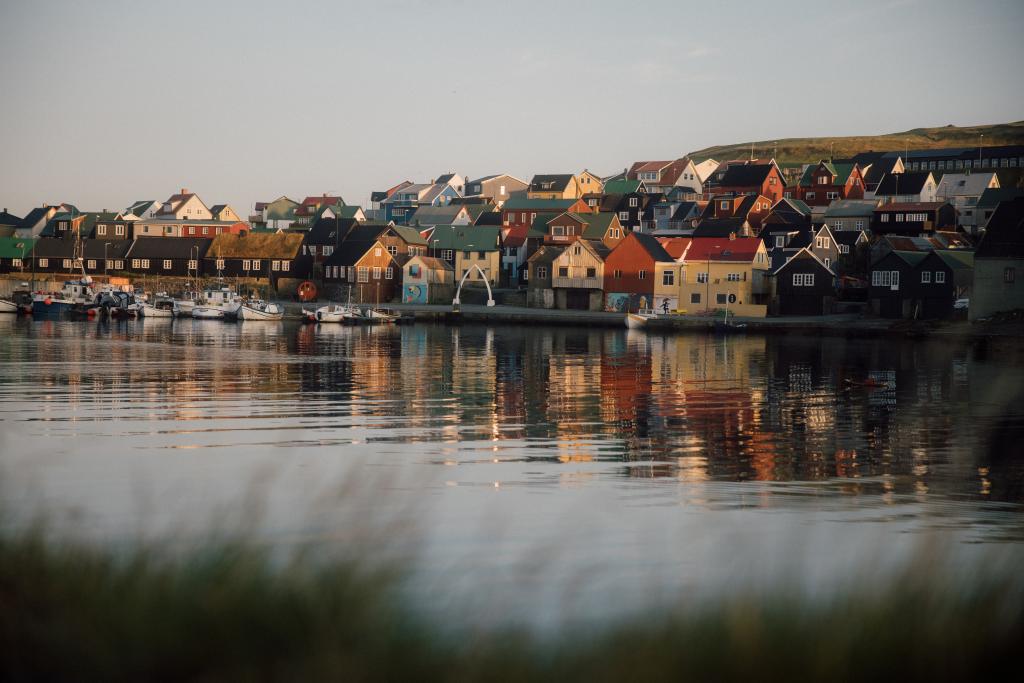 Colorful homes in Nólsoy, Faroe Islands. Harbor with boats and sunny surroundings. 