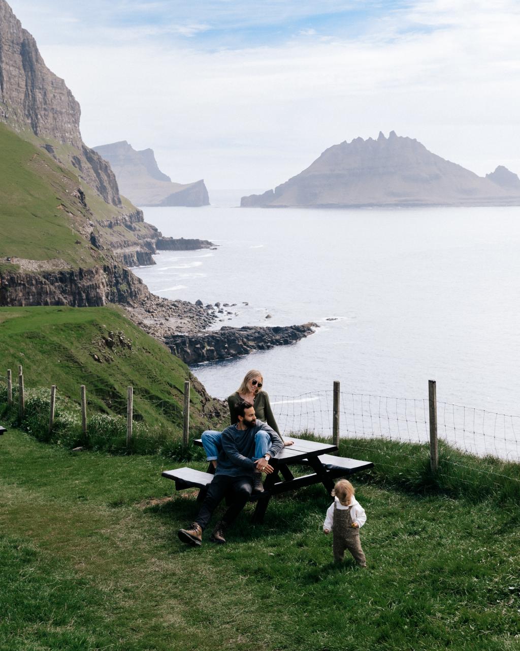 Family travels to the Faroe Islands. Child playing in the stunning green nature. 