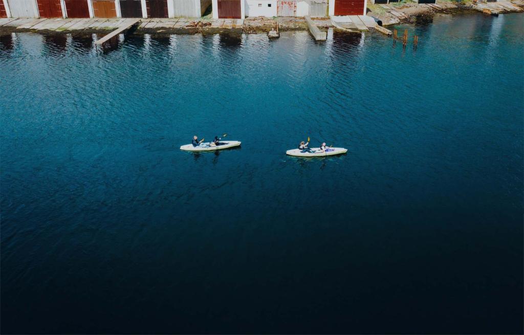 **Meta Description:**  
Experience the tranquility of kayaking in the picturesque harbor near Vágur, Suðuroy, Faroe Islands. Two kayakers paddle through calm ocean waters, surrounded by stunning coastal scenery and the charm of a traditional Faroese village.