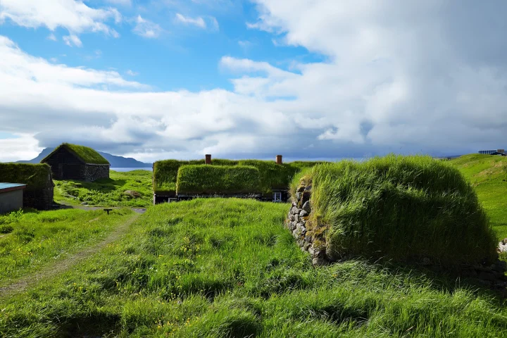 A view of the outhouses and farmhouse at the open-air museum Hoyvíksgarður. The buildings are covered with grass roof.