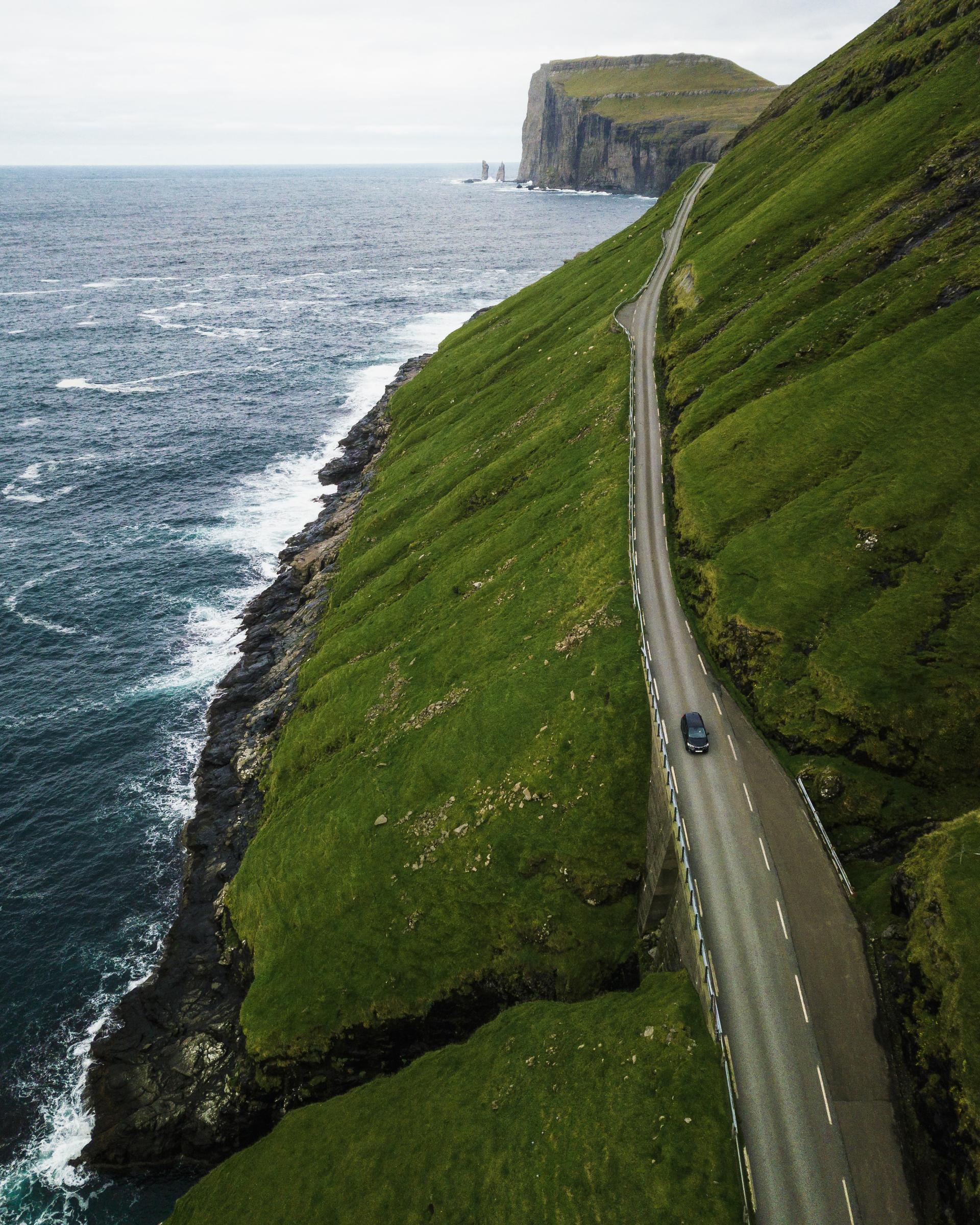 Thumbnail of - Car driving towards Tjørnuvík in the Faroe Islands. Stunning scenery from above of the shores 6 green hills. Taken by Saviour Mifsud